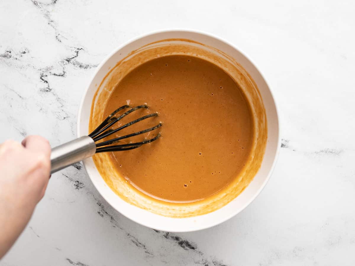 Peanut sauce in a bowl with a whisk.