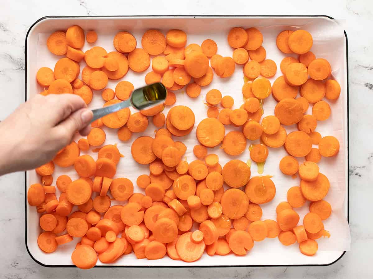 Overhead shot of sliced raw carrots in a sheet pan.