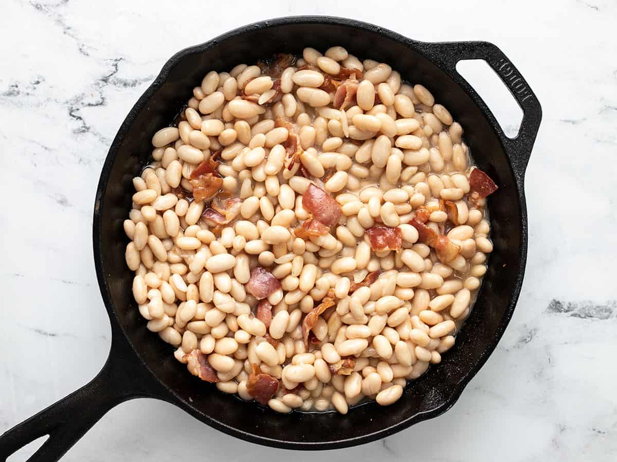 Beans added to skillet with cooked bacon.