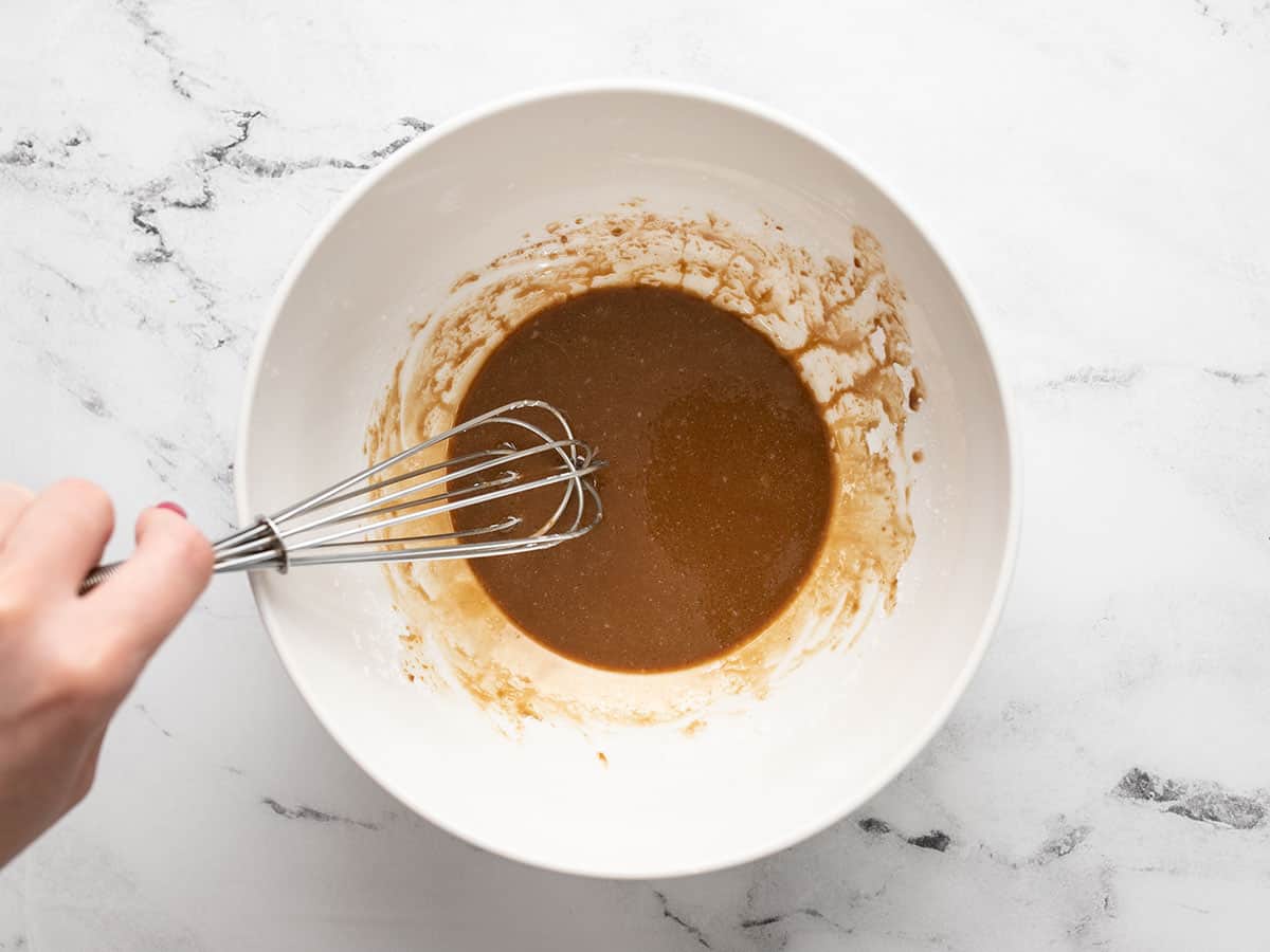 Seasoned cornstarch slurry in a bowl with a whisk.