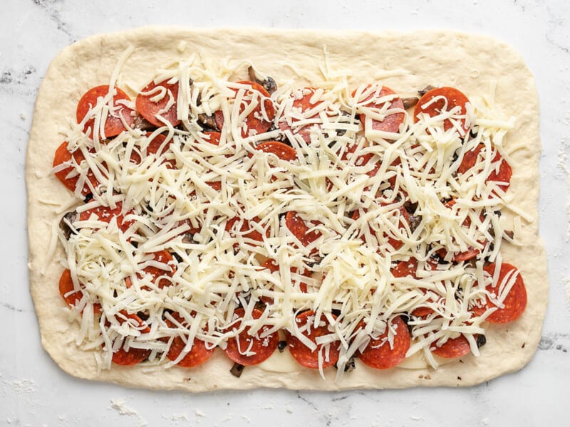 Pepperoni and mozzarella on pizza dough.