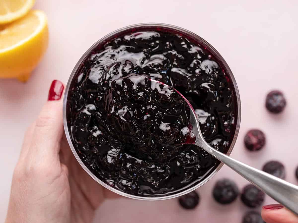 Overhead shot of blueberry sauce in a serving bowl with spoon in it.