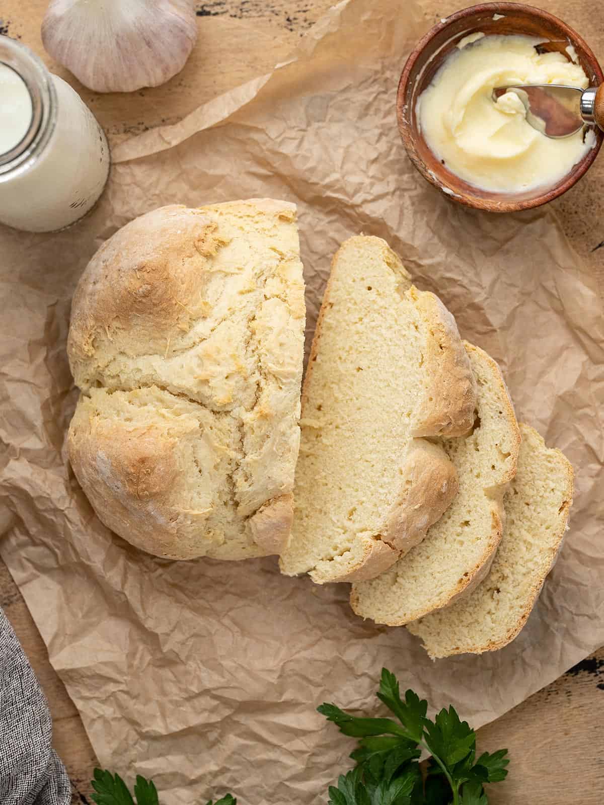 Overhead shot of baked easy soda bread sliced on parchment.