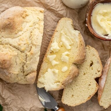 Overhead shot of baked easy soda bread sliced and buttered on parchment.