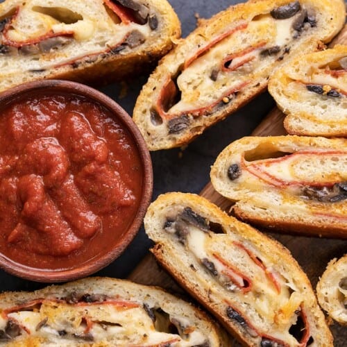 Overhead view of slices of stromboli around a bowl of pizza sauce.