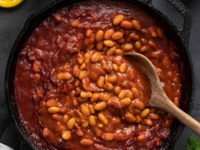 Overhead view of baked beans in the skillet with a wooden spoon.