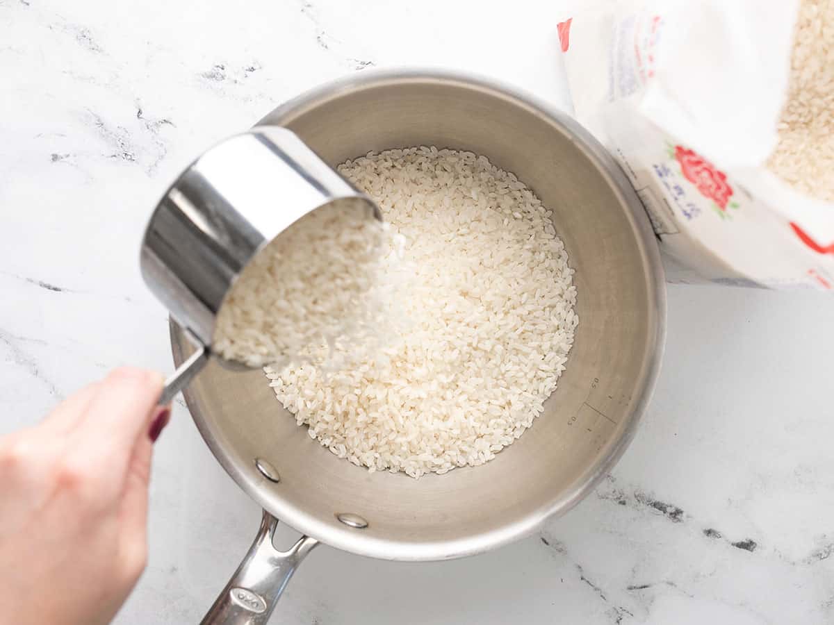 Rice being poured into a sauce pot.