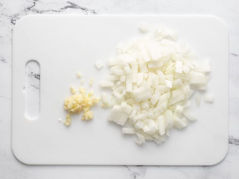 Diced onion and minced garlic on a cutting board.