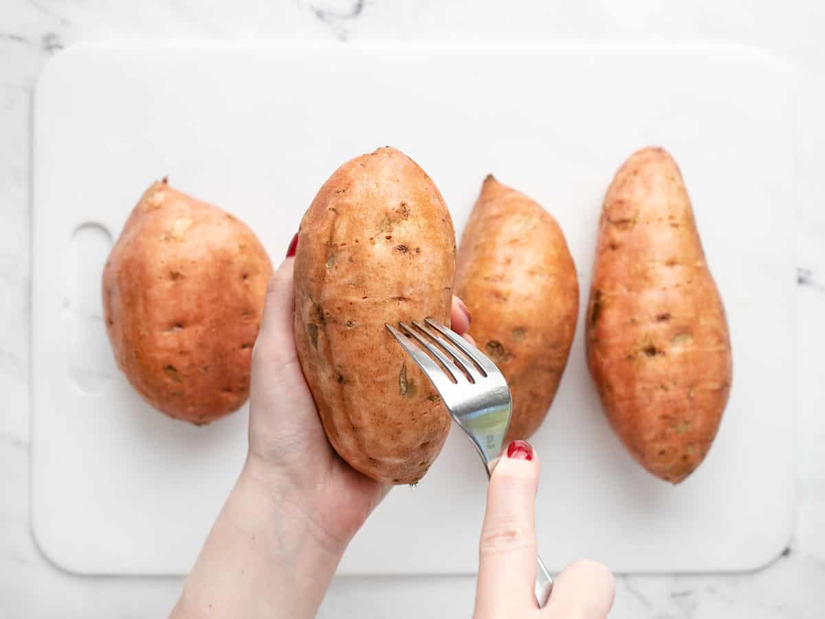 Sweet potatoes being pricked with a fork. 