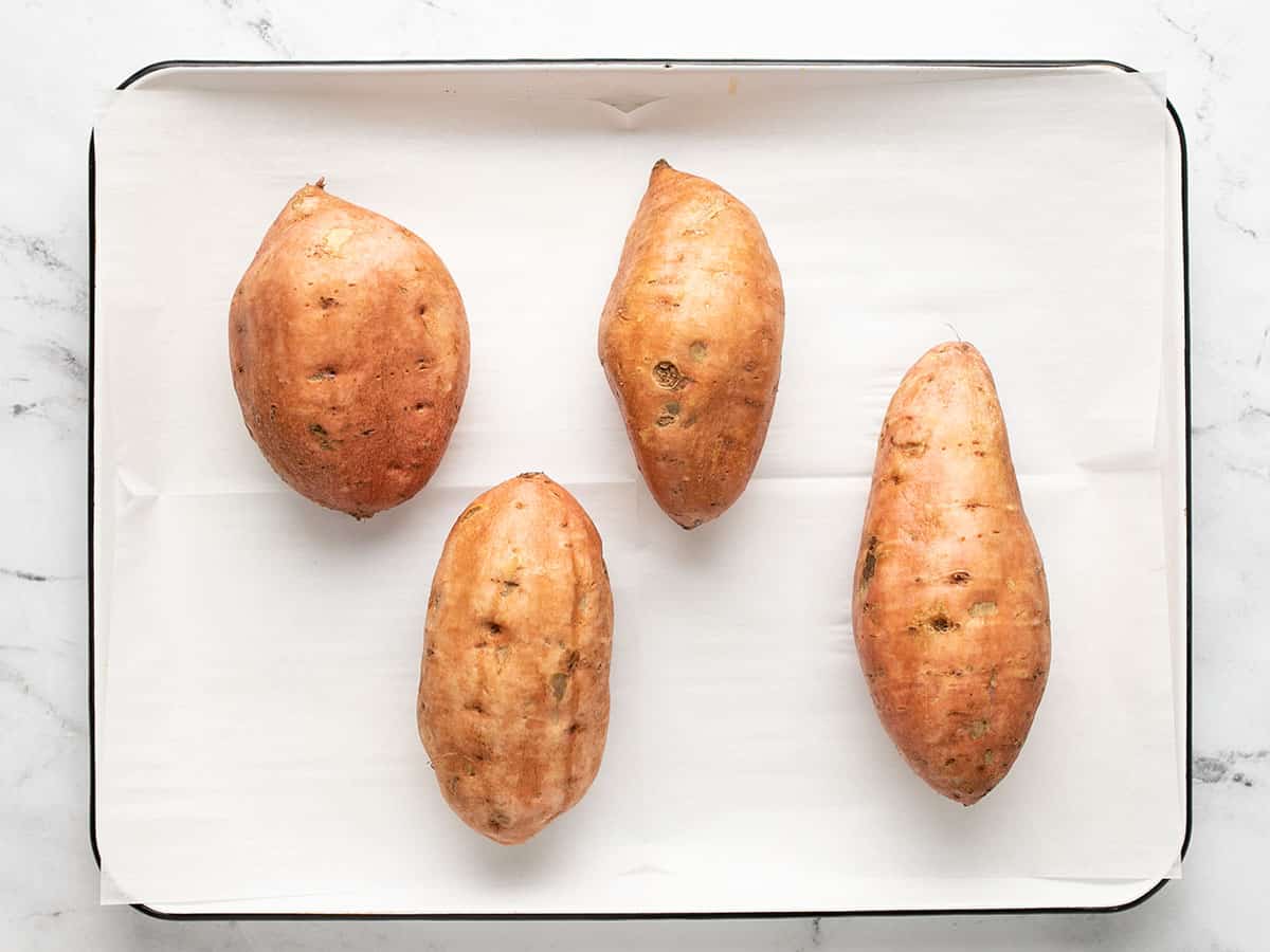 Sweet potatoes on a parchment lined baking sheet. 
