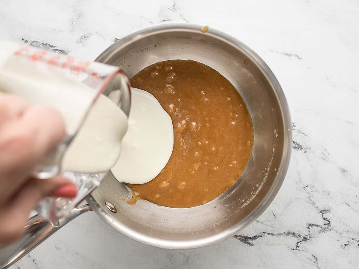 Cream being put in caramel sauce in a pot.