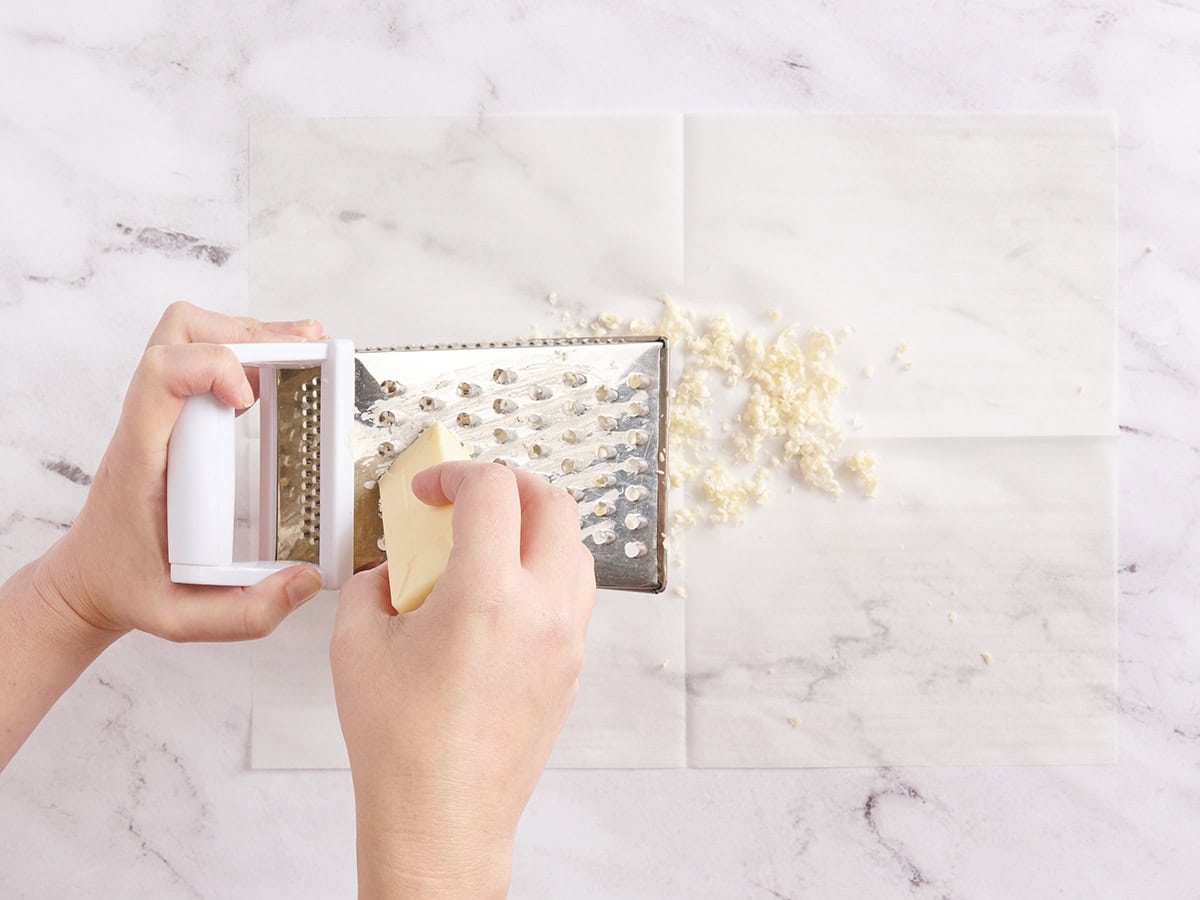 Butter being grated with a box grater.