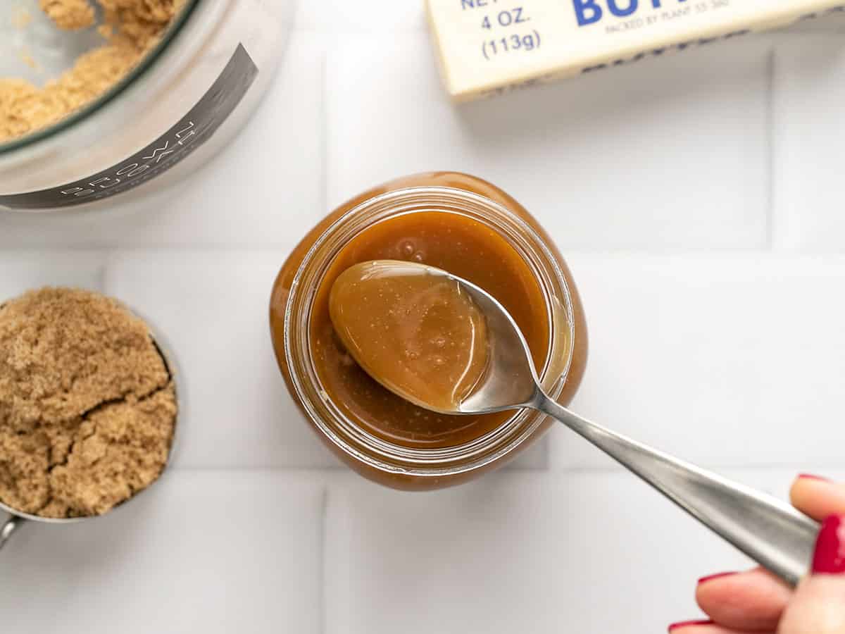 Overhead shot of a spoon taking caranel sauce out of a mason jar.