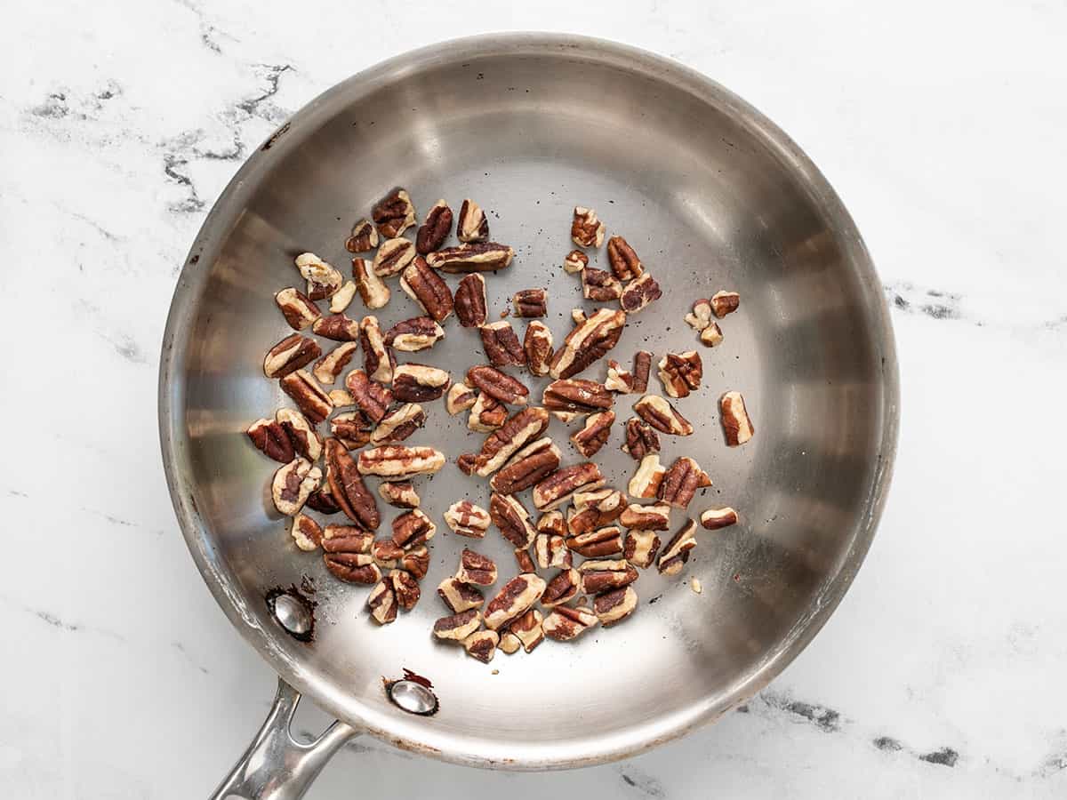 Chopped pecans being toasted in a skillet.