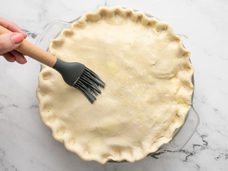 Overhead shot of brushing egg wash on a pie.