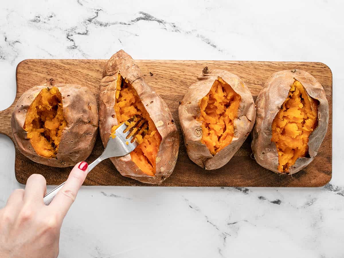 Sweet potatoes being mashed in their skins.