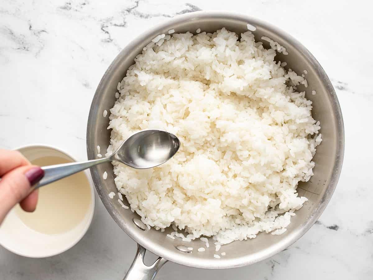 Il condimento viene spruzzato sul riso nella pentola.