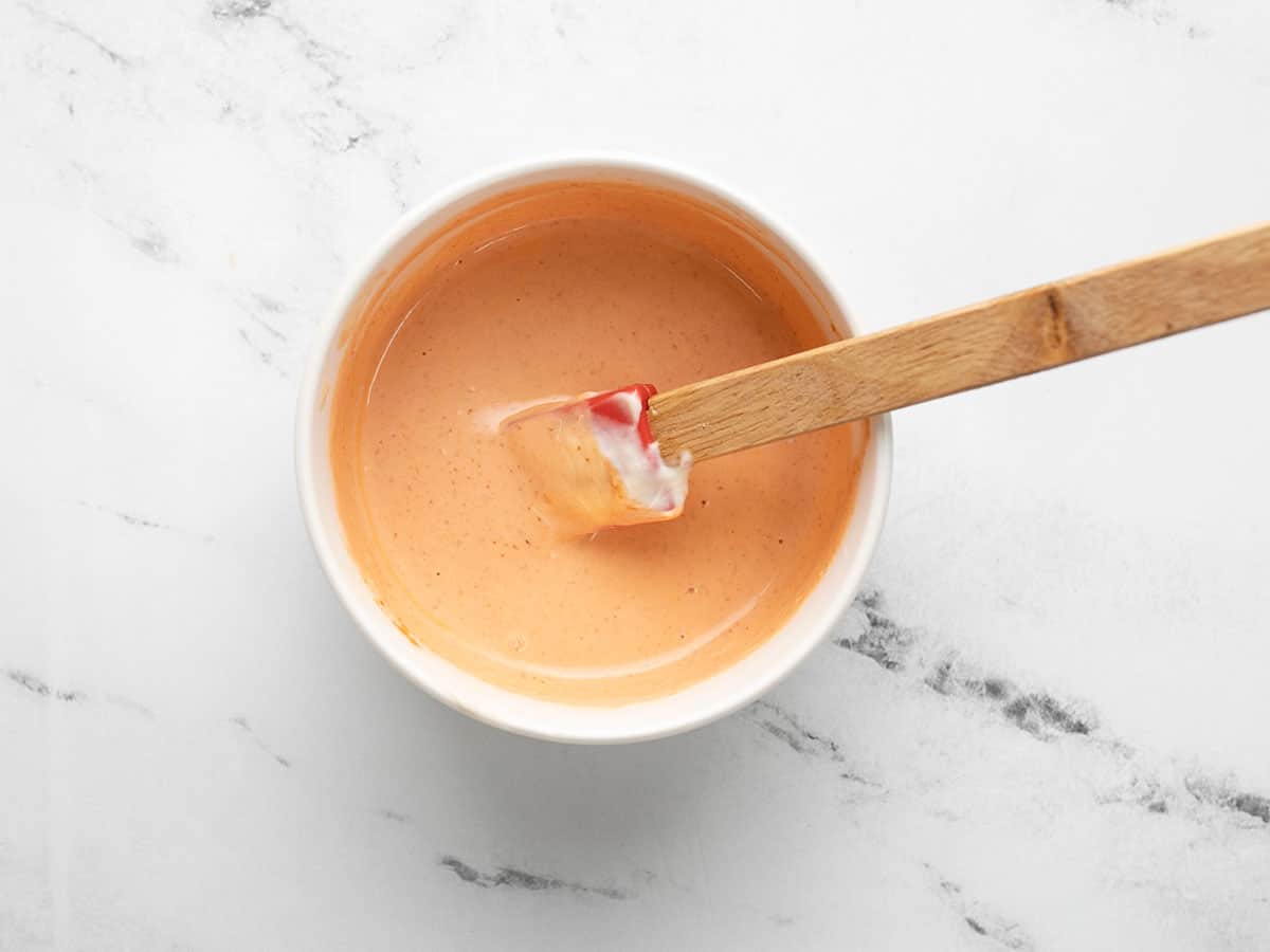 Sriracha mayo being stirred in a small bowl.