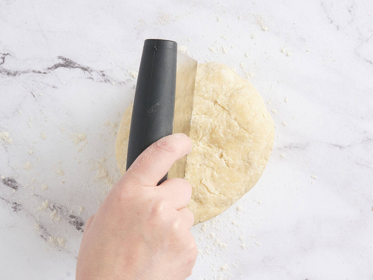 Pie dough being cut into two portions.