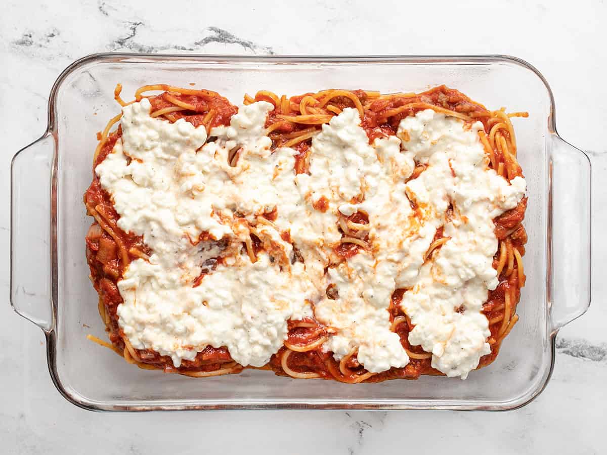 First two layers of baked spaghetti in the casserole dish. 