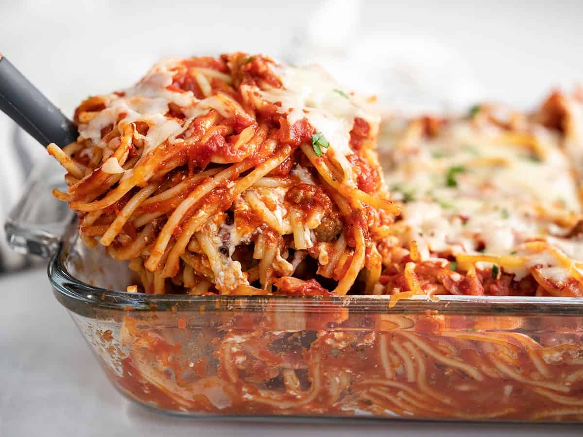 Side view of baked spaghetti being lifted out of the casserole dish.