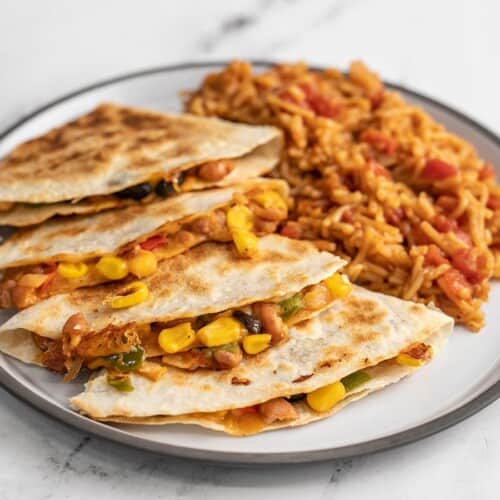 Side view of a plate full of bean quesadillas and Spanish rice.