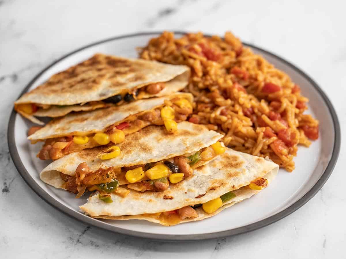 Side view of a plate full of bean quesadillas and Spanish rice.
