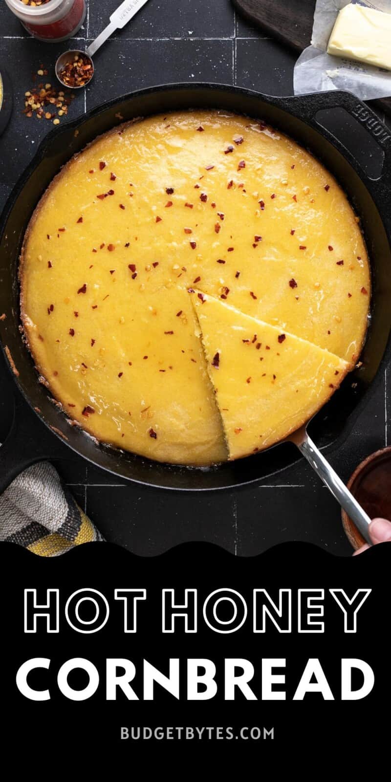 Overhead shot of hot honey cornbread in a cast iron skillet with a wedge being taken out..