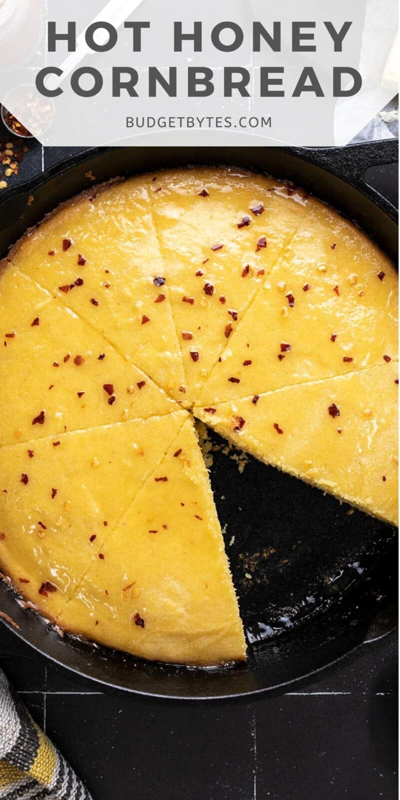 Overhead shot of hot honey cornbread in a cast iron skillet with a wedge taken out.