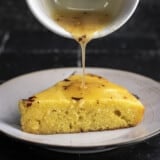 Side shot of hot honey butter being drizzled on cornbread slice.