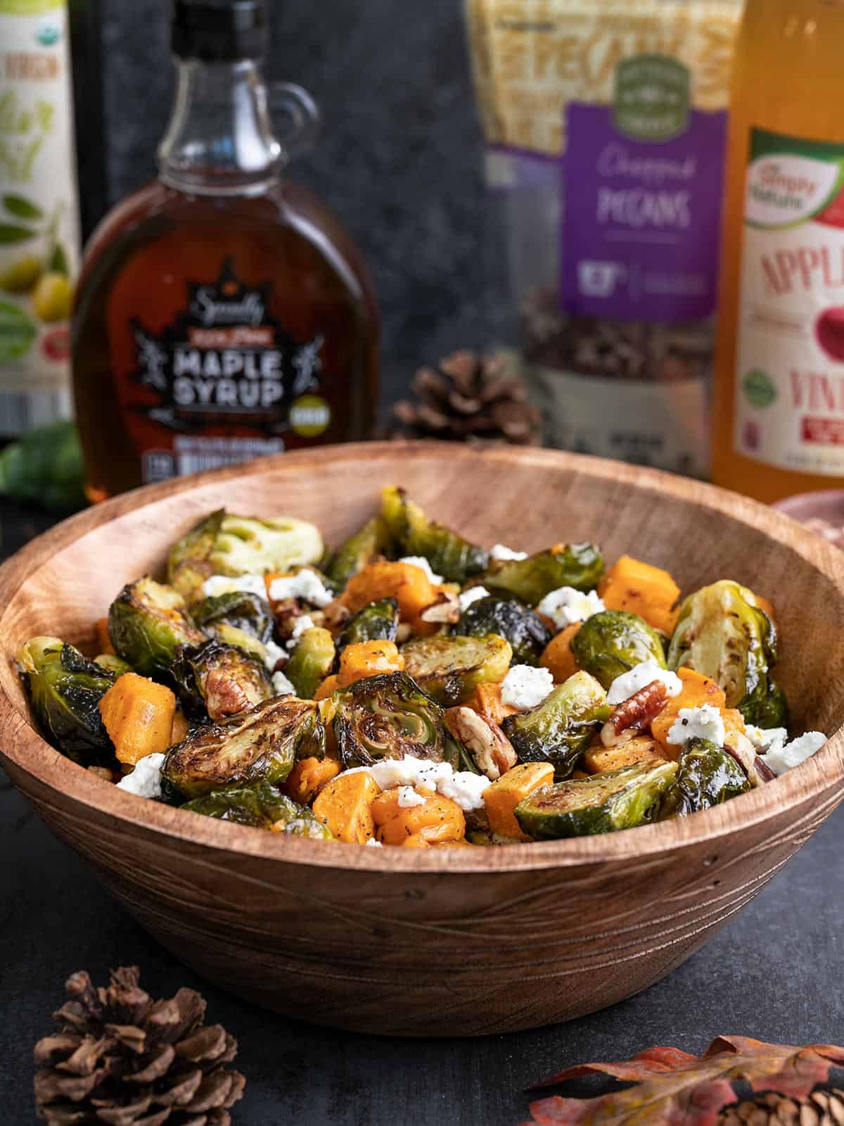 Side view of a bowl of Roasted Brussels Sprouts Salad with ingredients in the back.