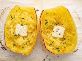 Overhead shot of roasted spaghetti squash dressed with butter and chopped Italian parsley.