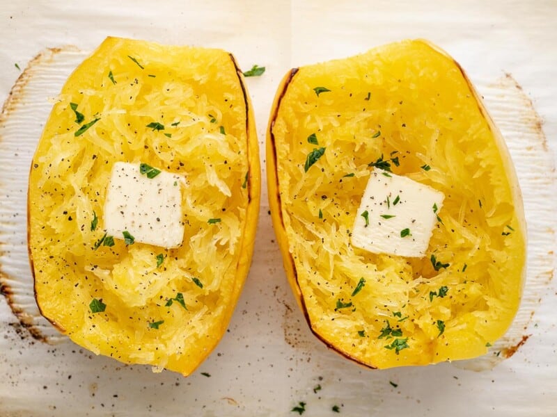 Overhead shot of roasted spaghetti squash dressed with butter and chopped Italian parsley.