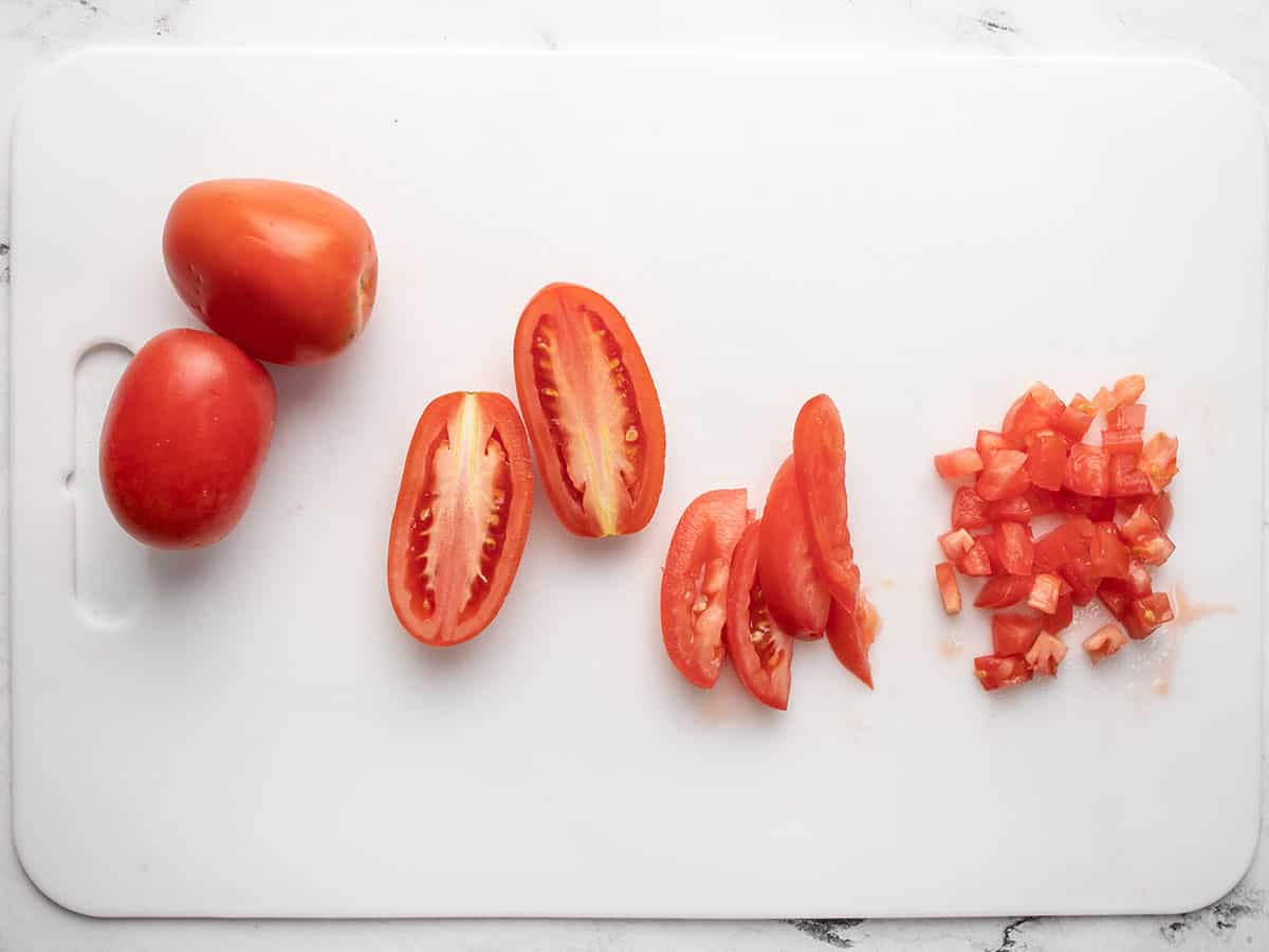 Overhead shot of sliced and diced tomatoes on a white chopping board.