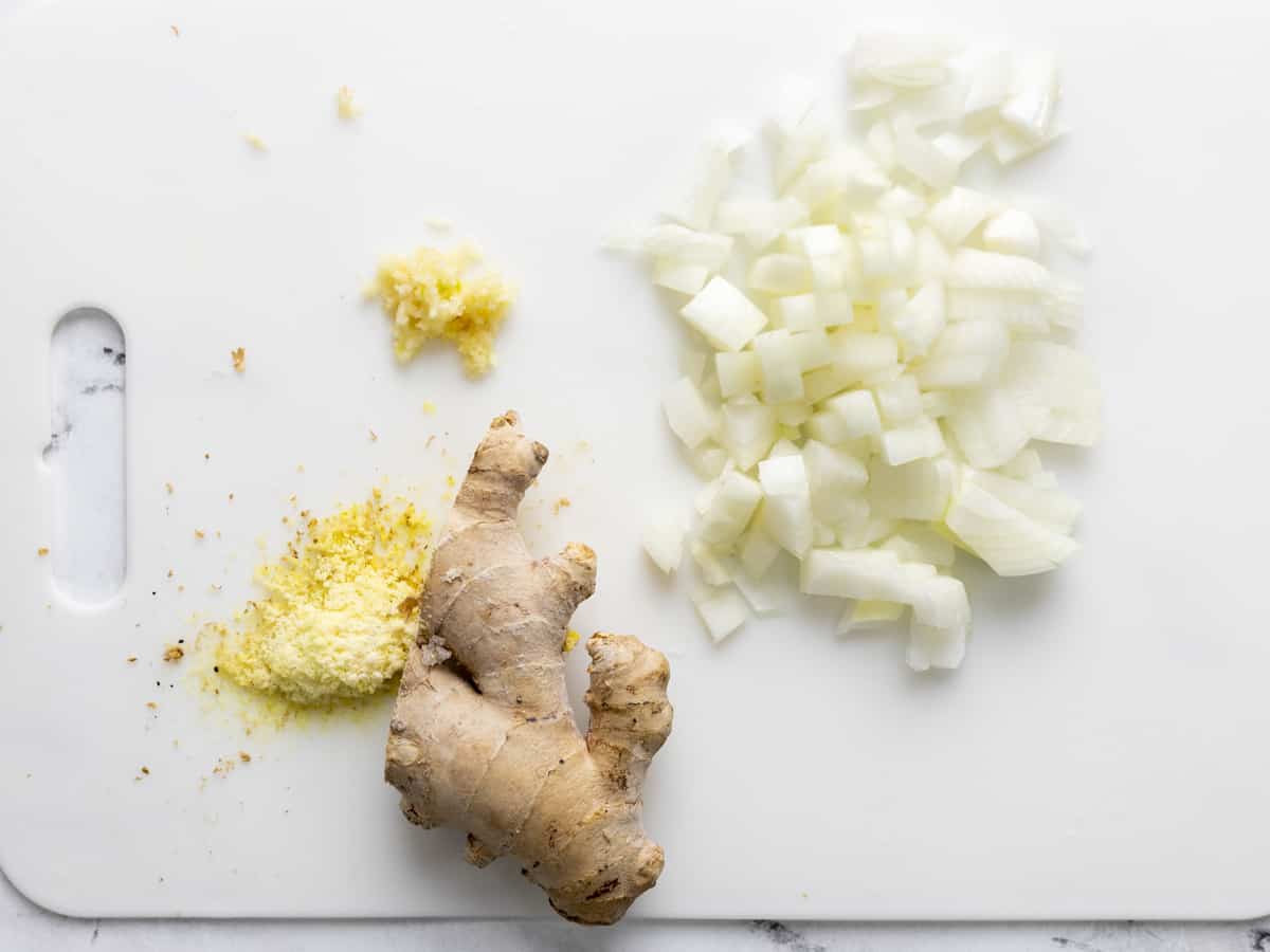 Diced onion, minced garlic, and grated ginger on a cutting board. 