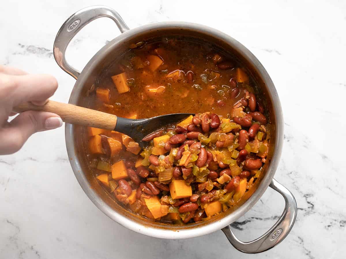 Overhead shot of finished red beans in a silver pot with a spoon scooping a cup full.