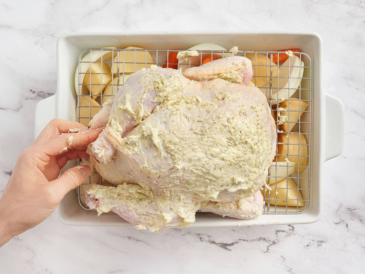 A hand trussing a chicken without twine.