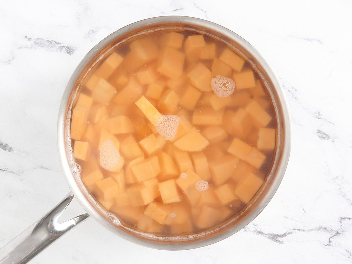 Cubed sweet potatoes in water in a sauce pan.