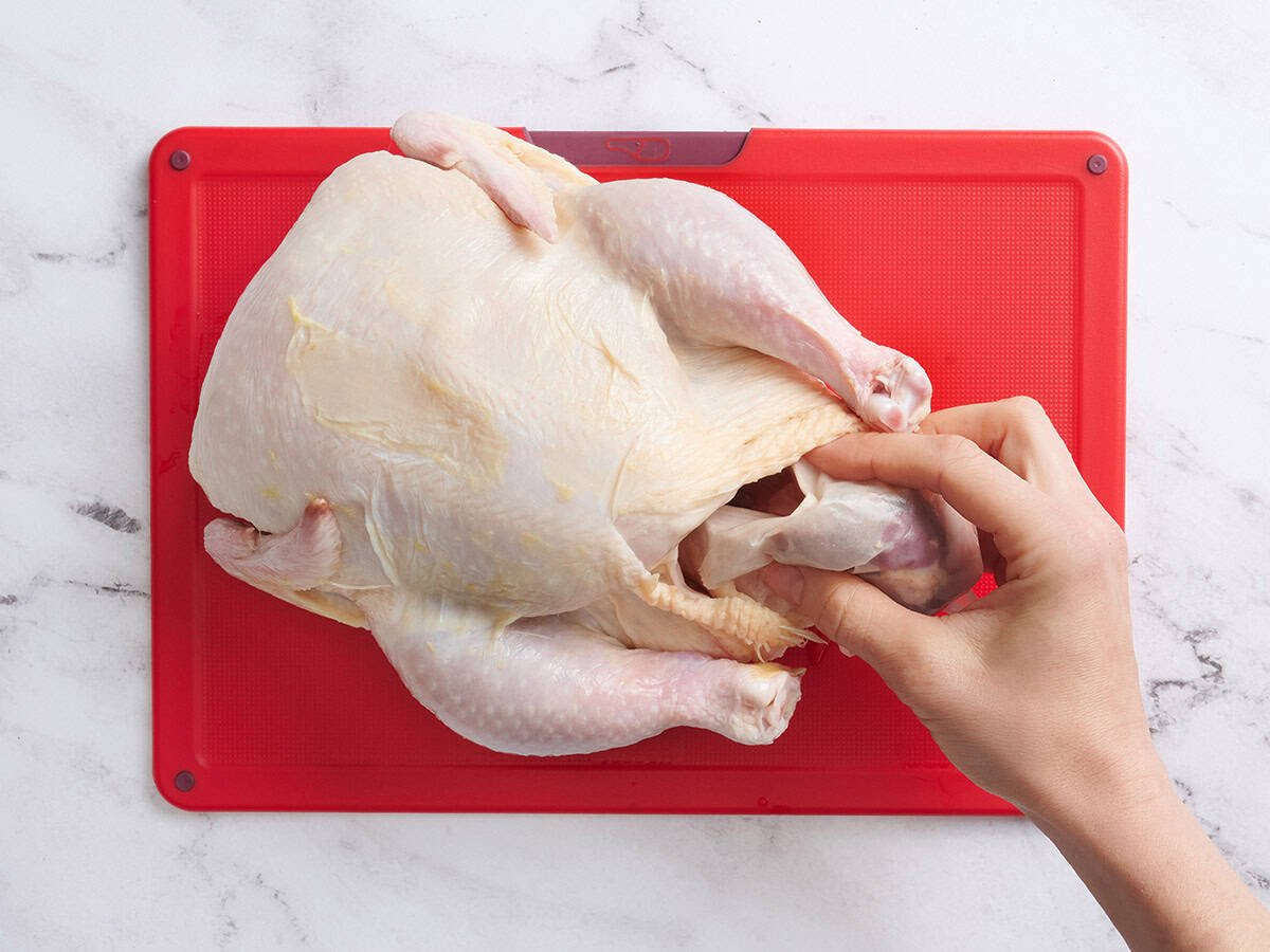 A hand removing the giblets from a whole turkey.