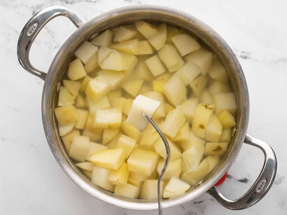 A fork piercing a potato from the pot.