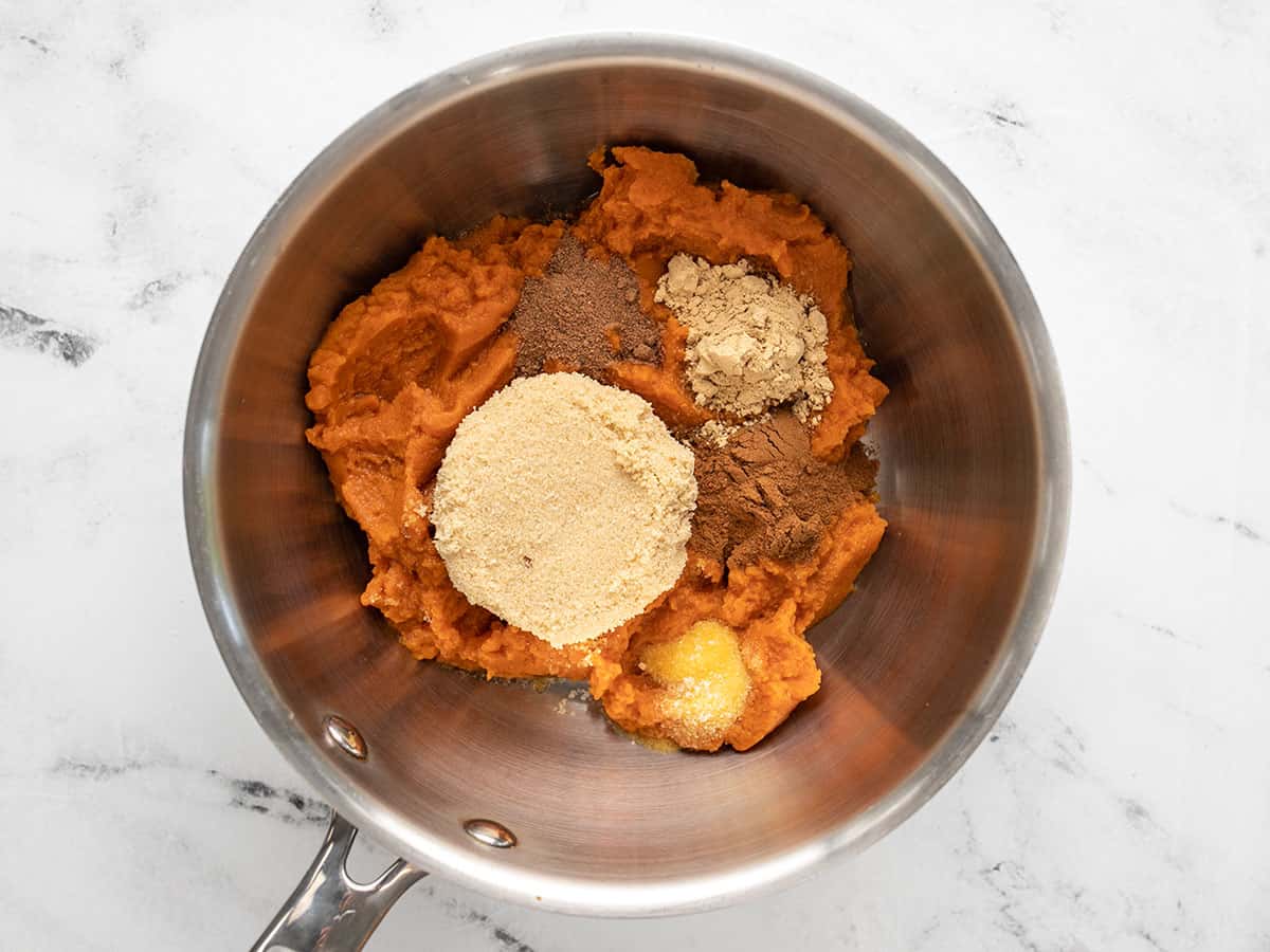 Pumpkin purée, sugar, and spices in a pot, not stirred together. 