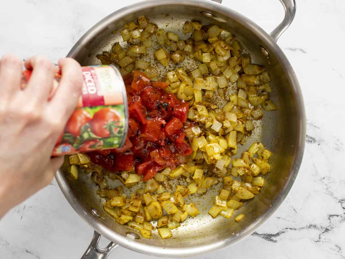 Diced tomatoes being poured into the skillet.