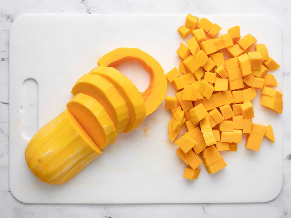 Butternut squash sliced and cubed on a cutting board.