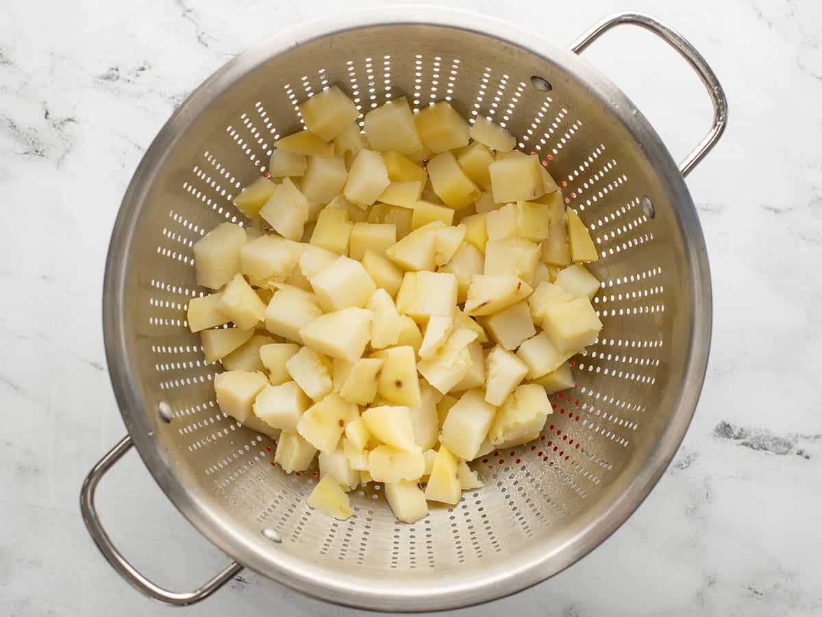 Boiled potatoes in a colander after rinsing again.
