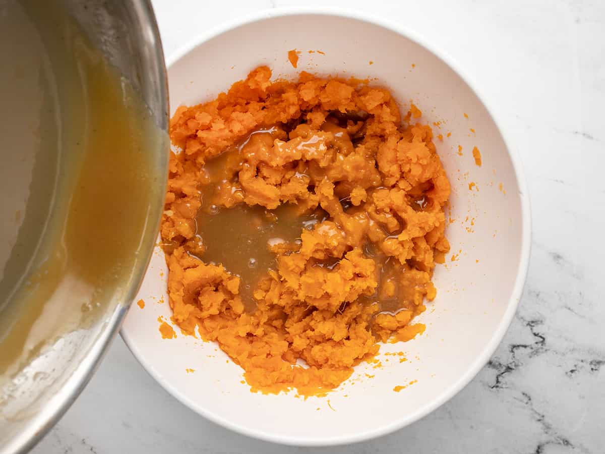 Overhead shot of caramel being poured out of a pot into sweet potato mash.