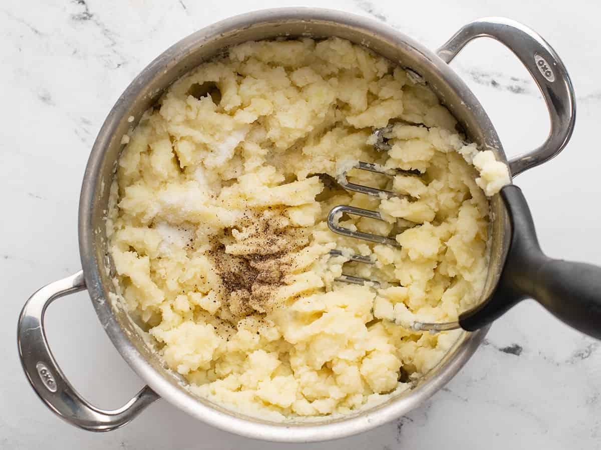 Salt and pepper added to mashed potatoes in the pot.
