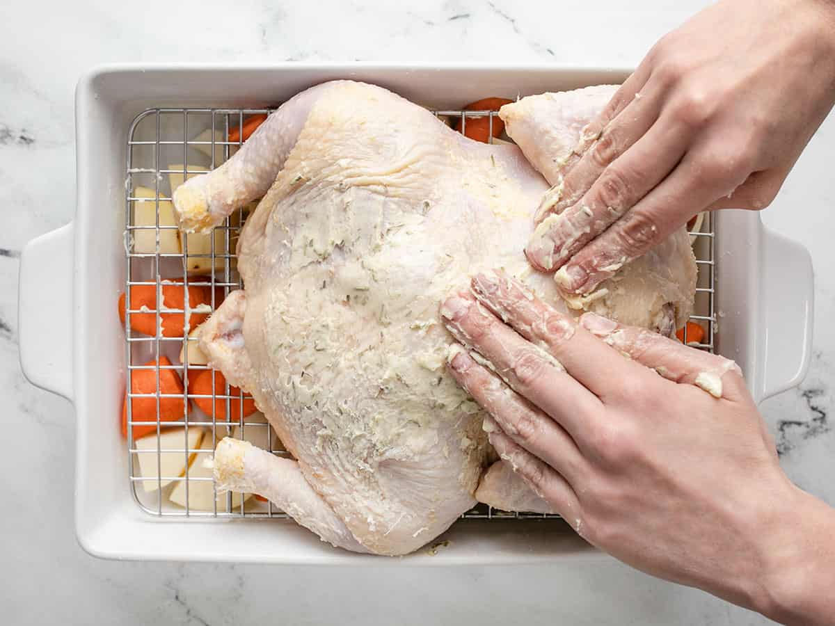 Overhead shot of chicken being rubbed down in butter.