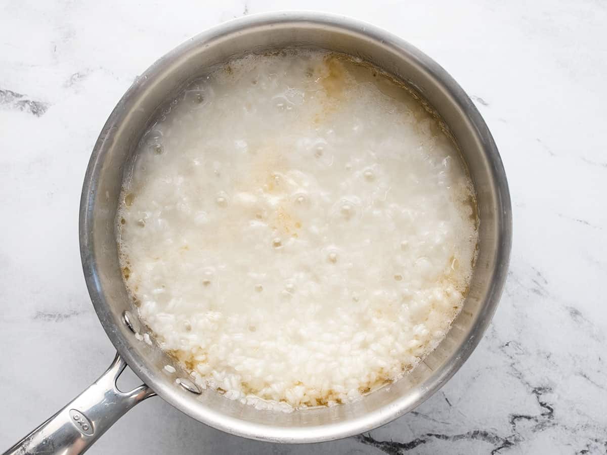 Overhead shot of a silver pot of rice with steam vents on the surface of the rice