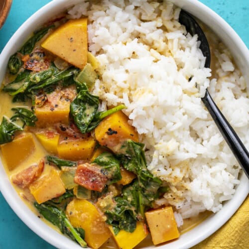 Close up overhead view of butternut squash curry in a bowl with rice.