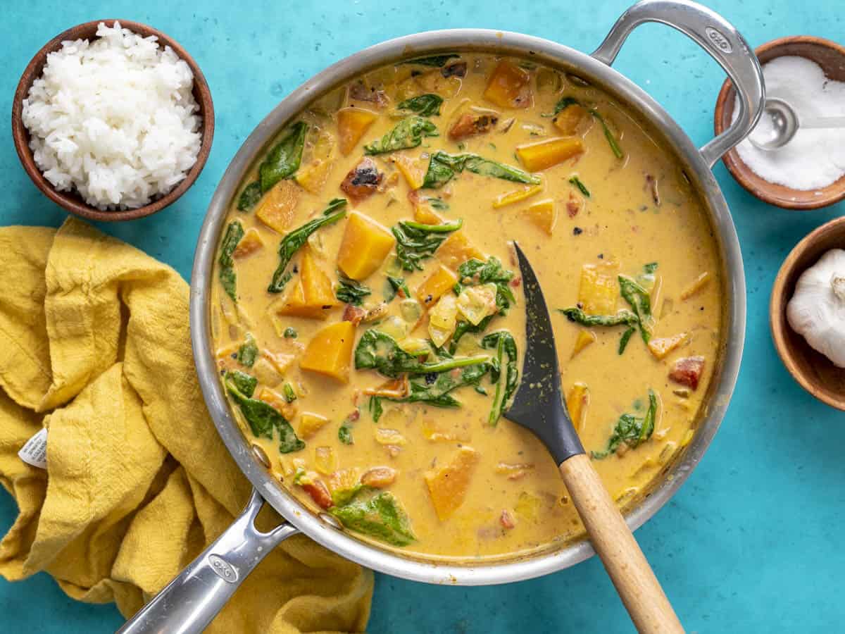 Overhead view of a skillet full of butternut squash curry with a spatula.